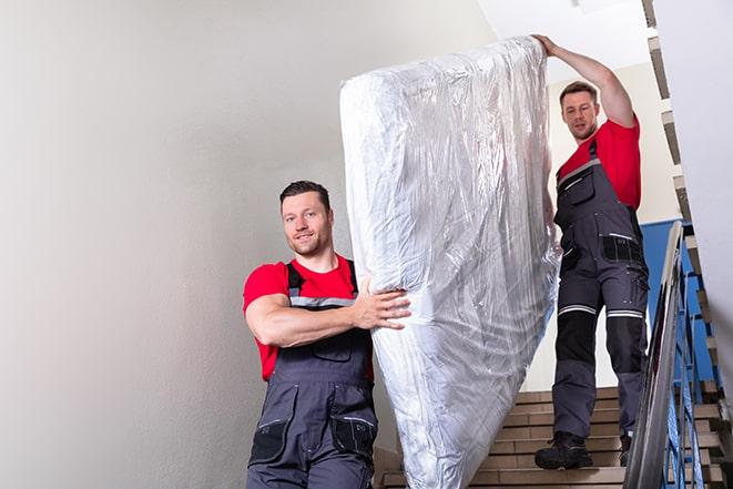 team of workers lifting a box spring out of a house in Oak Park, MI